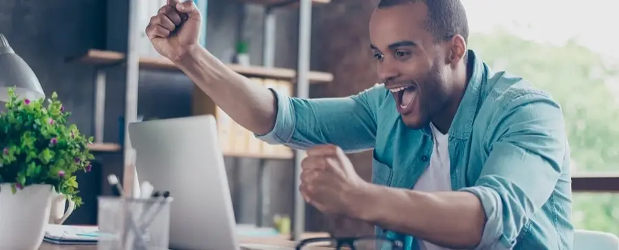 Someone cheers behind a laptop screen.