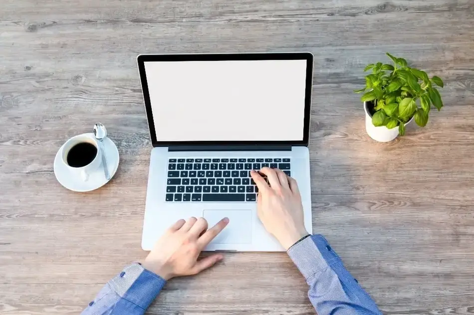 Pessoa usando um computador com uma xícara de café ao lado
