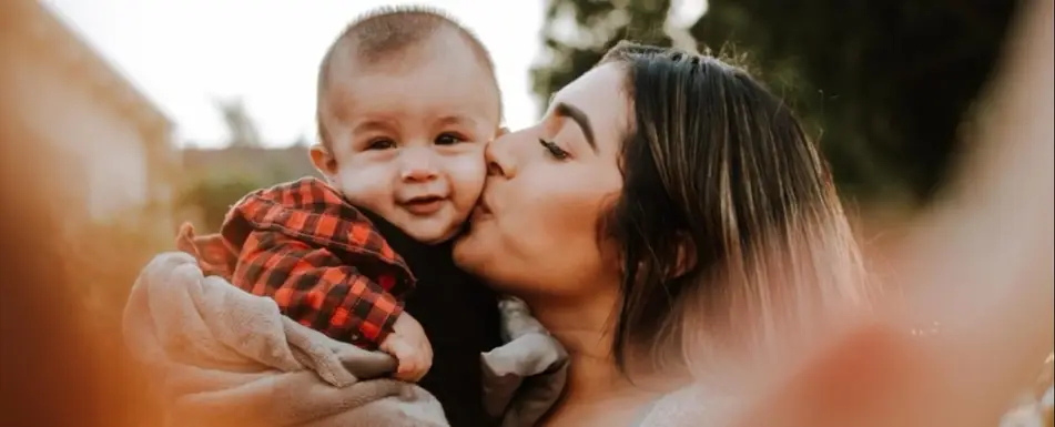 A woman kissing a baby.