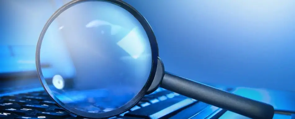A magnifying glass resting on its side in the center of a keyboard.