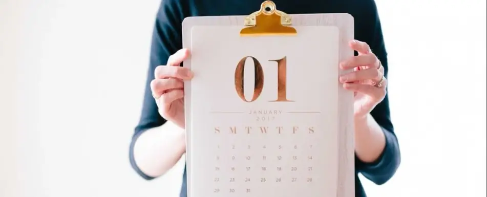 A person holding up a calendar.