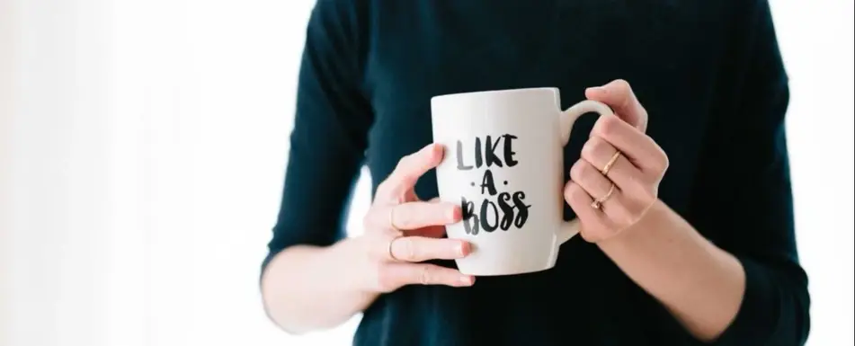 A woman holding a white mug that says, "Like a boss."
