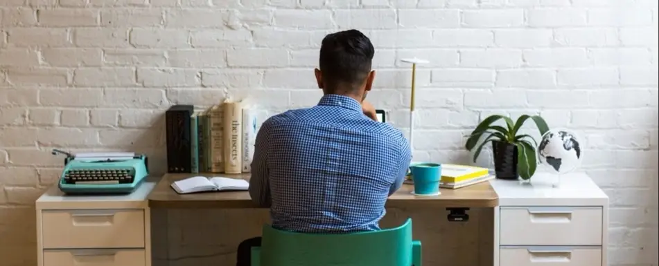 A man with short hair sits at his work desk.