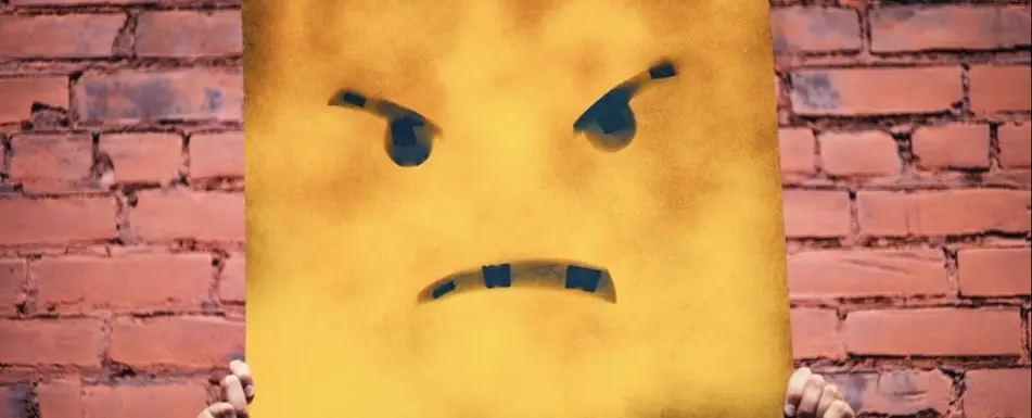 Someone holds up a mask of an angry face.