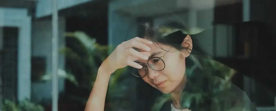 A photograph of an Asian woman looking stressed, as if contemplating a sensitive topic at work.