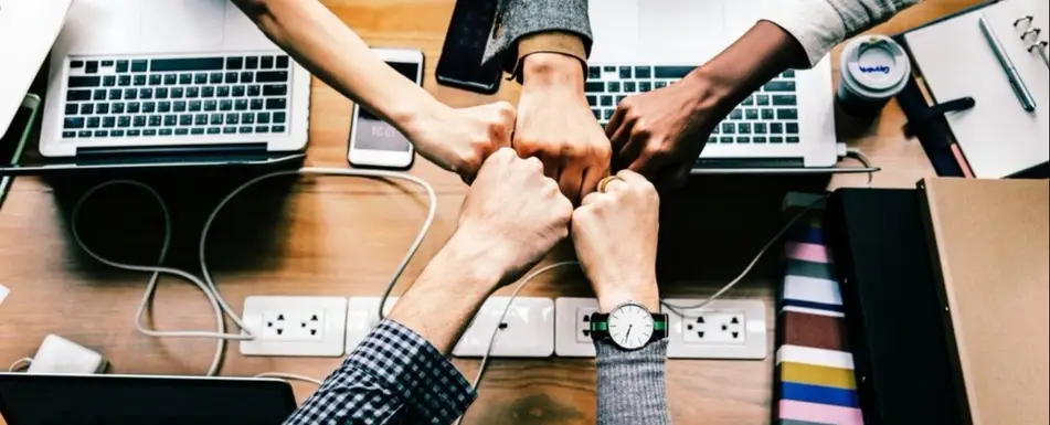 Close up of a team of hands fist bumping.