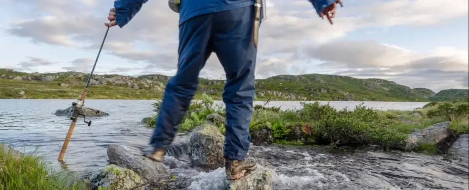 A fisherman standing on rocks in the water.