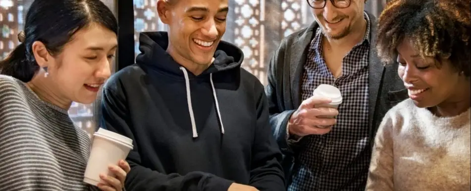 A group of people laugh at a video on a phone.