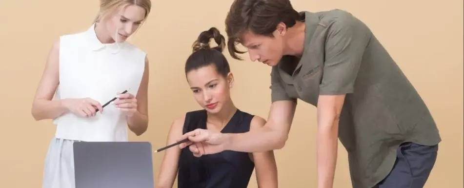Coworkers gathered around a computer.