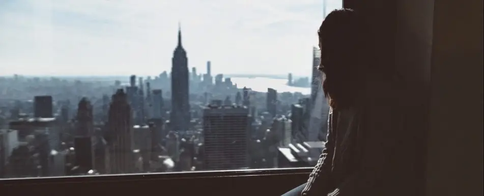 A woman looks out the window at  New York city.