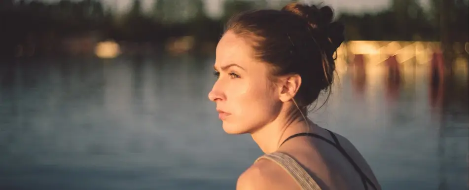 woman sitting by water looking to the side
