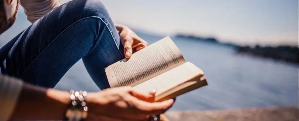 A woman reads by the waterside.