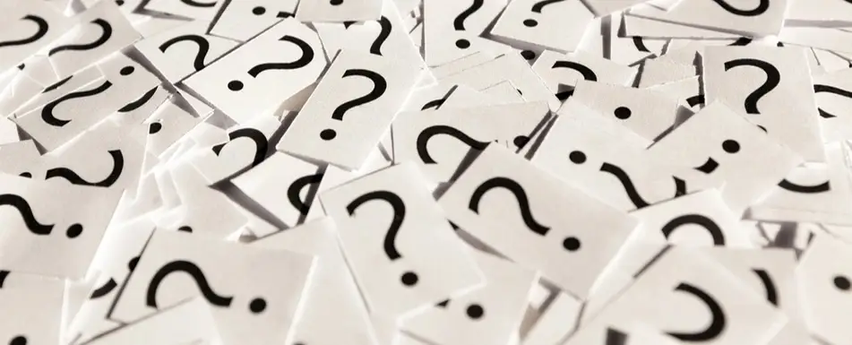 A pile of a papers with question marks on it.