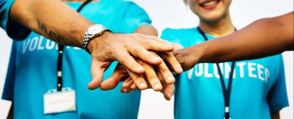A group of volunteers with their hands in huddle.
