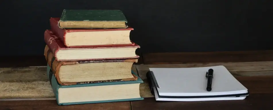 pile of books with a writing pad next to them