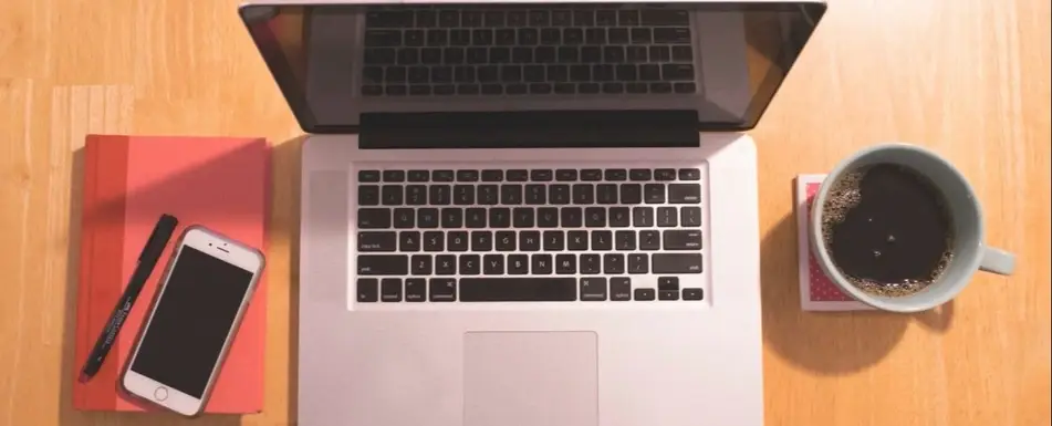 Overhead shot of a laptop with a cup of coffee next to it.