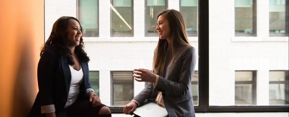 Two people discussing by a window.