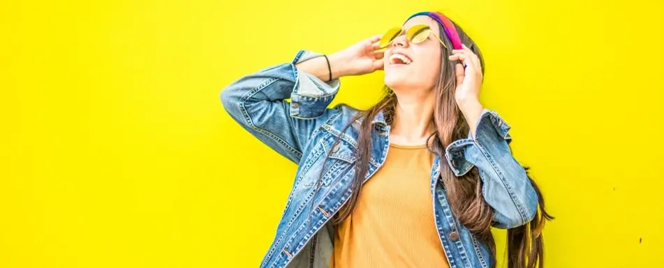 A woman in sunglasses looks up smiling.