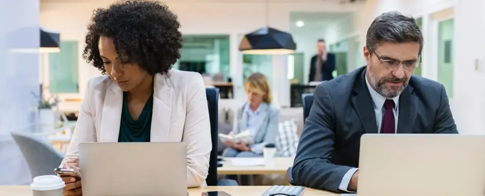 man and woman working at a desk, not looking at each other