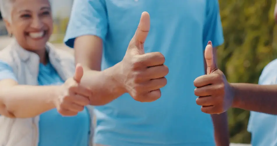Group of volunteers hold their thumbs up
