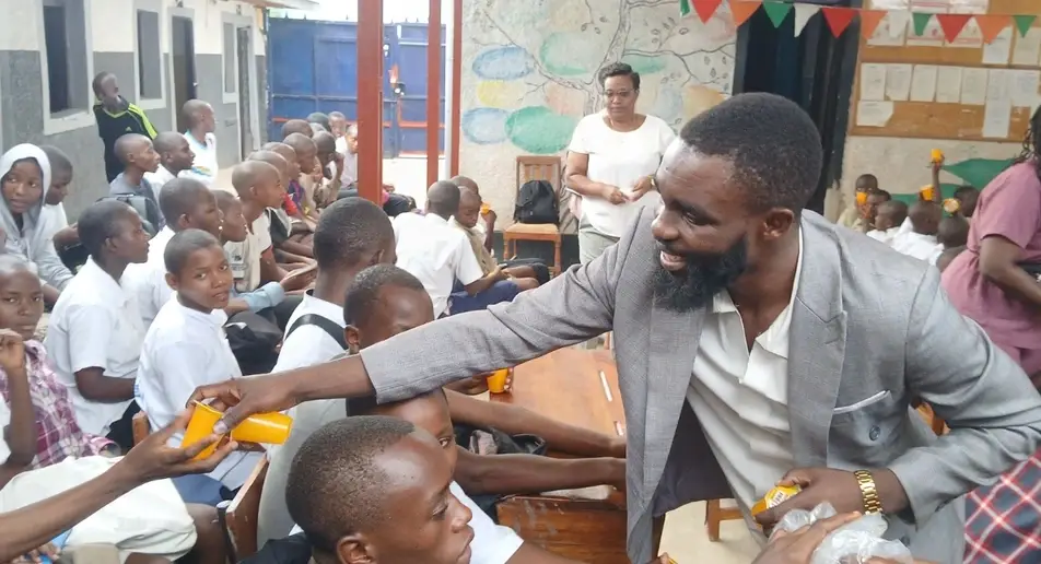 Thierry N. from Burundi passes out porridge to children at a local school.