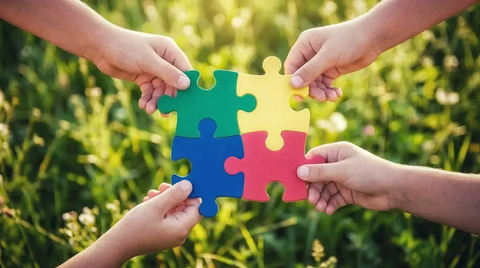 4 hands each holding puzzle pieces put together