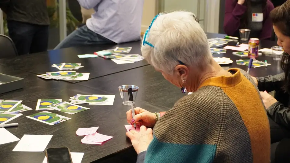 Volunteer writes a card to a friend for Idealist Day