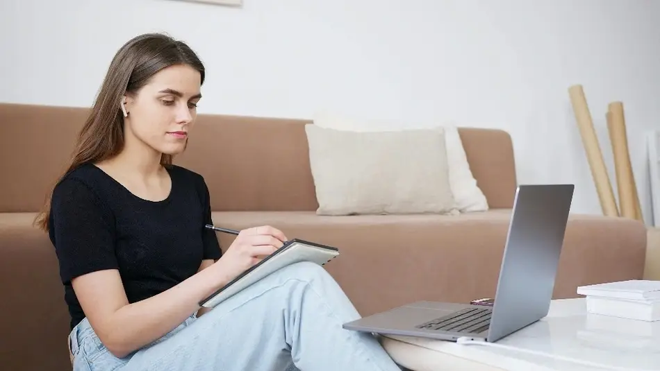 Mujer usando una laptop y tomando notas