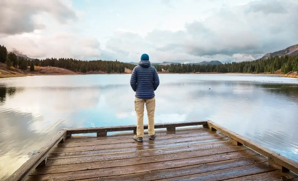 Hombre meditando frente a un lago.