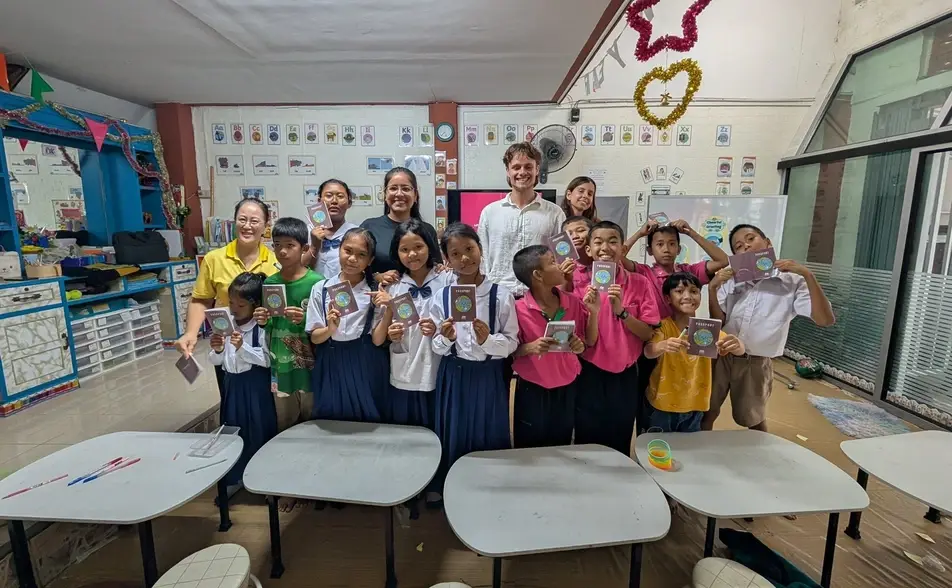 Estudiantes de una clase con personas voluntarias mostrando sus pasaportes de aprendizaje