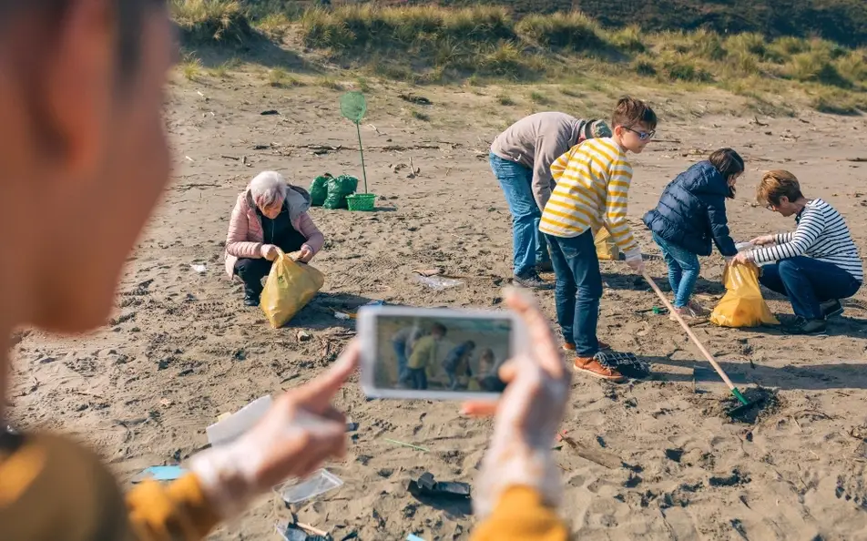 Un joven toma fotografías a un grupo de personas voluntarias limpiando la playa