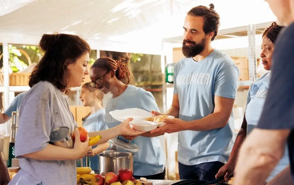 Personas voluntarias entregan comida a quien lo necesita.