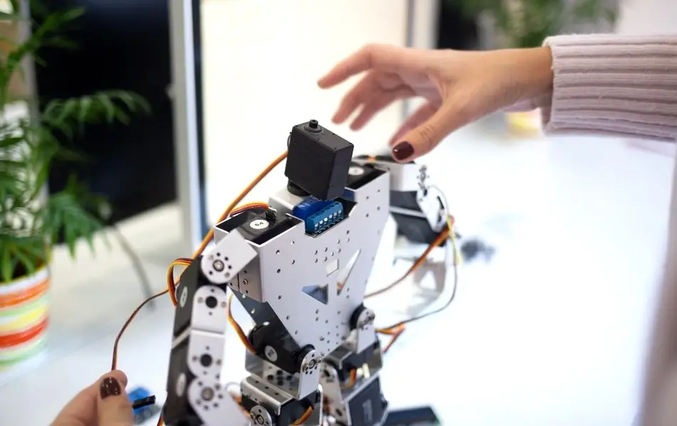 Manos de mujer construyendo un robot.