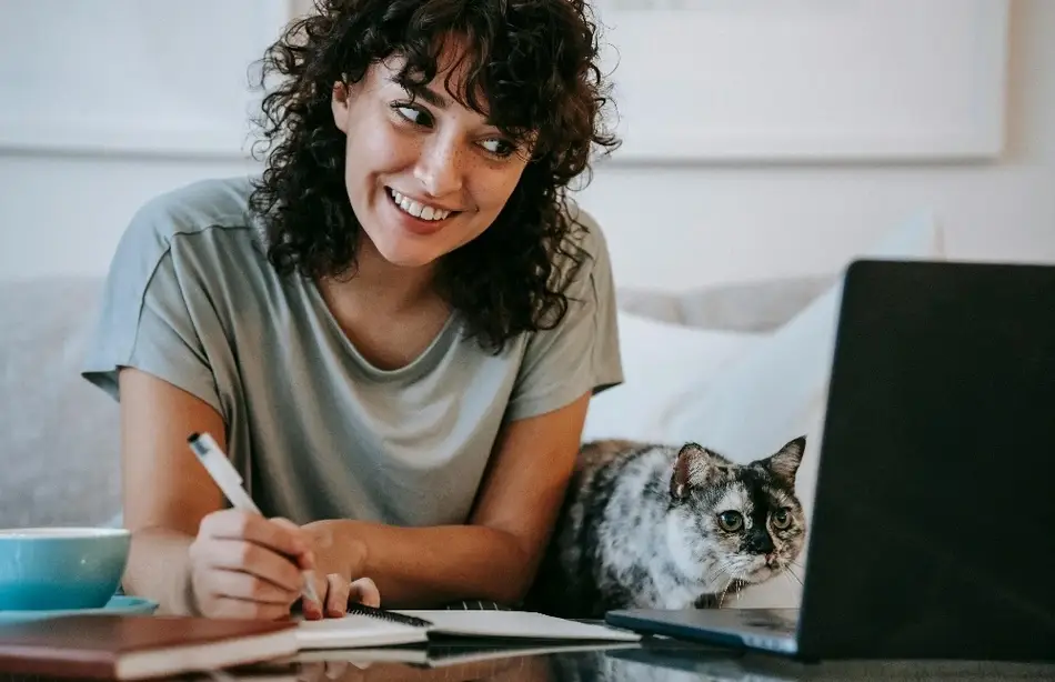 Mujer sonriendo y escribiendo en un planner