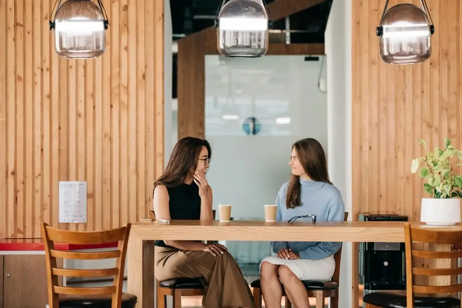 Dos mujeres sentadas conversando y tomando café