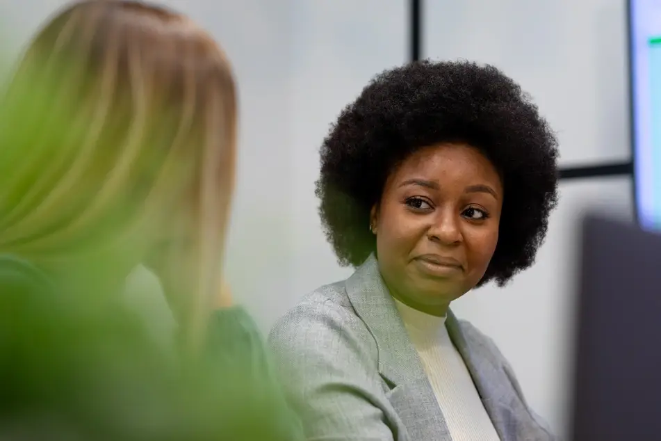 A Black woman works with a co-worker at the office