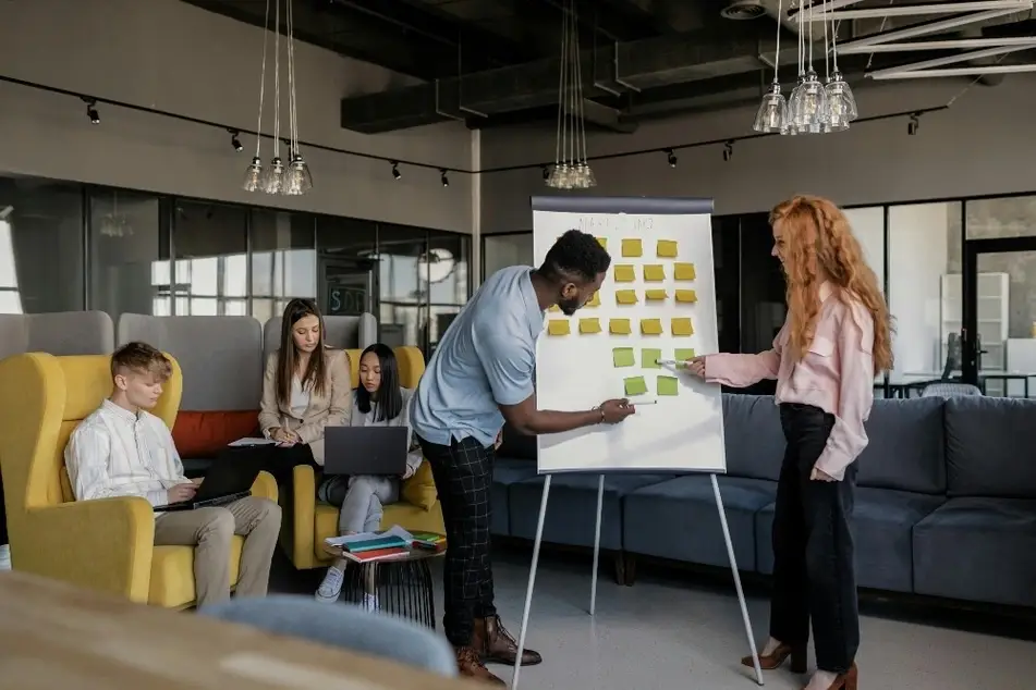 Equipo reunido alrededor de una pizarra con post its en una oficina