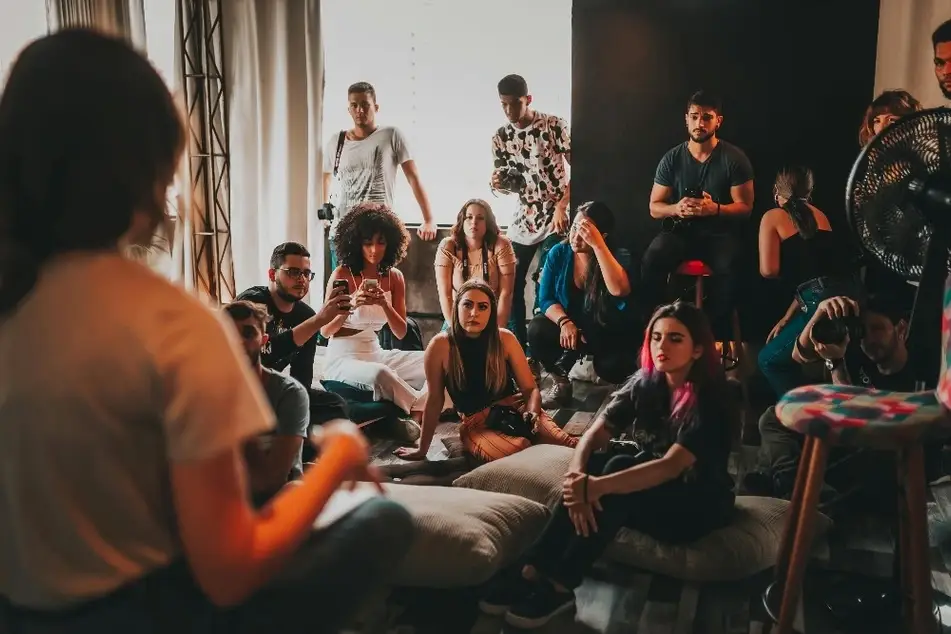 Grupo de personas reunidos alrededor de una mujer hablando
