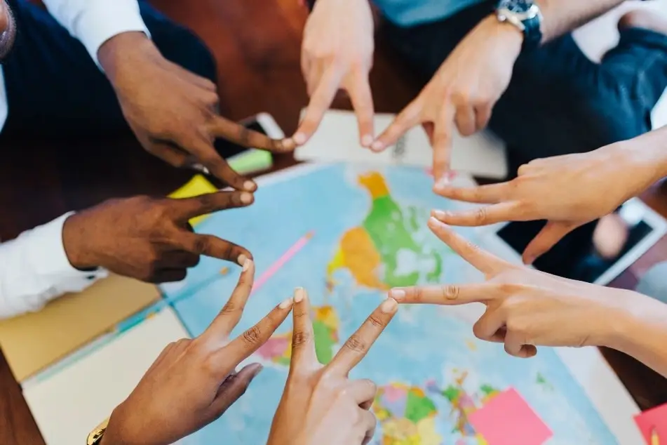 Manos de personas de diferente origen étnico unidas sobre un mapa del mundo