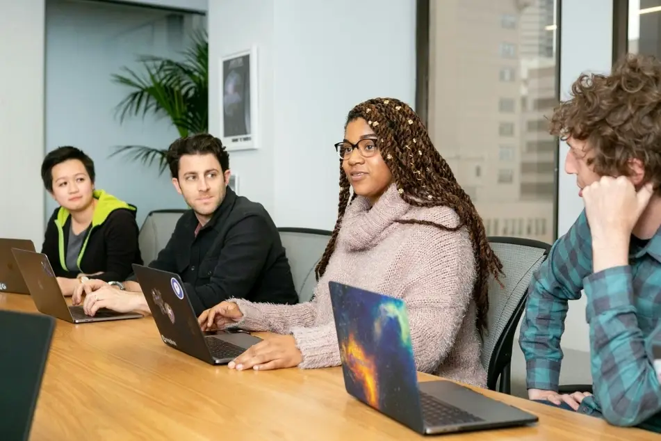 4 people with laptops, sitting at a table
