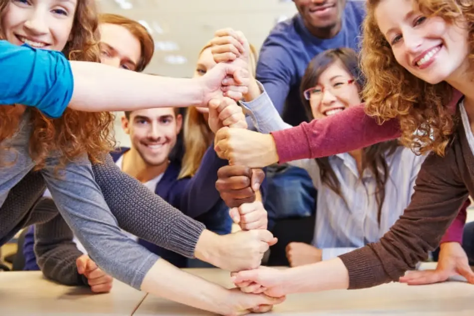 Equipo de varias personas uniendo el puño de sus manos