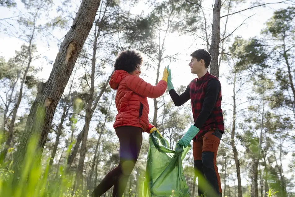 Two volunteers high-five after cleaning up the local park through a volunteer opportunity.