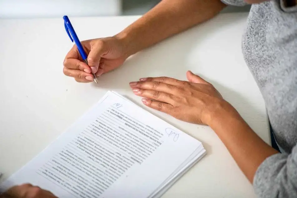 Manos firmando un contrato con tinta azul.