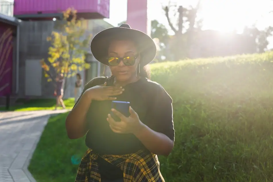 Black woman looks at phone and smiles
