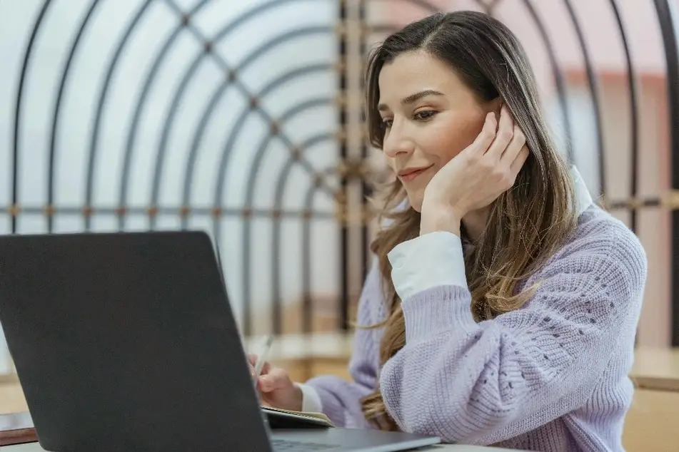 Mujer sonriendo mientras trabaja en su laptop