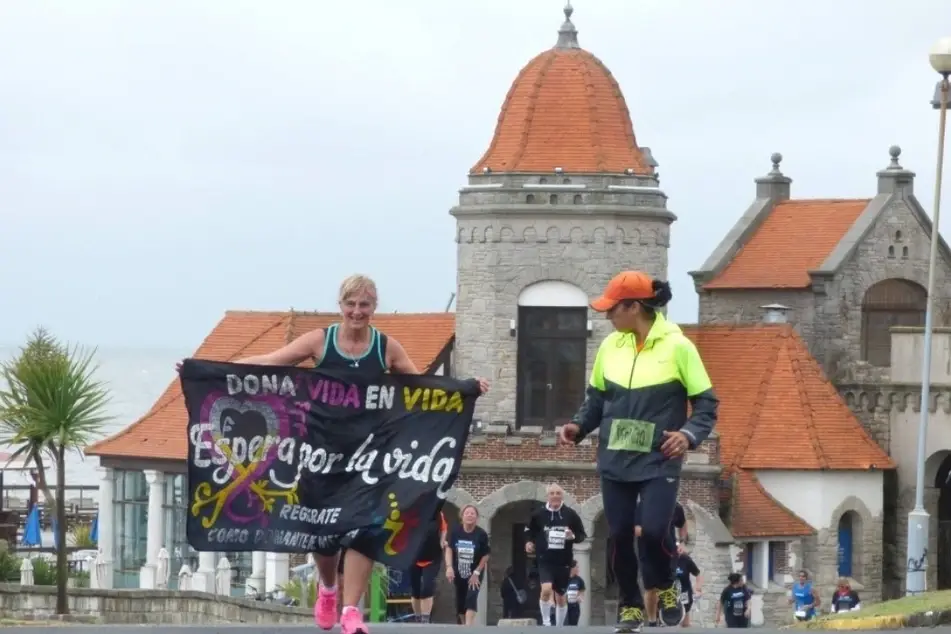 Una mujer corriendo mientras lleva un letrero que dice Don Vida en Vida