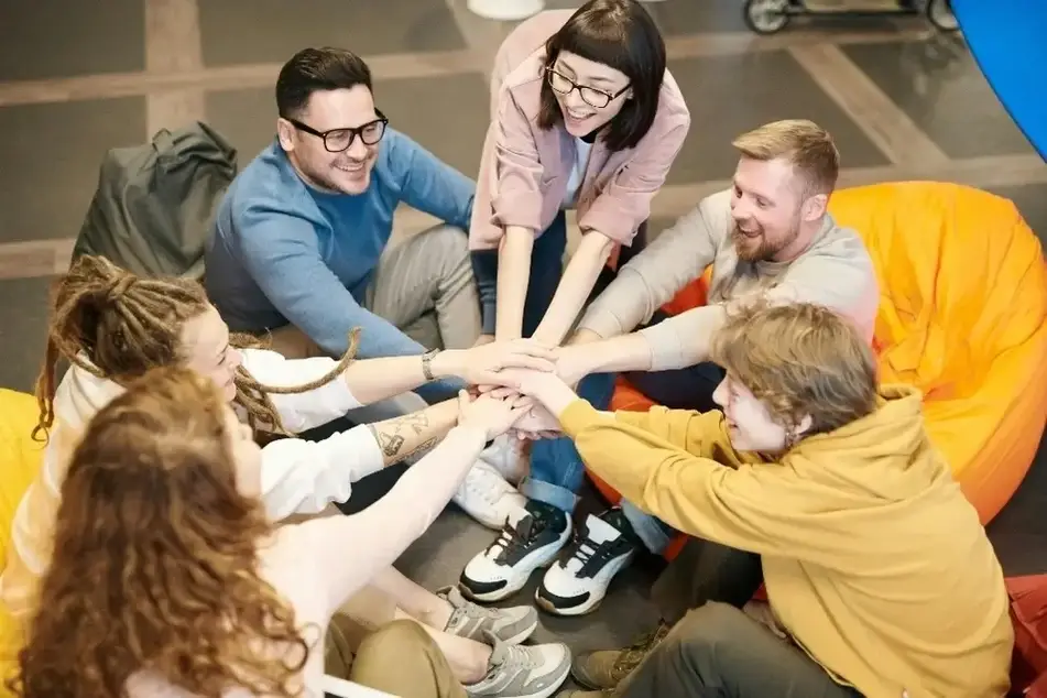 Group of people bringing their hands together in the center of their circle