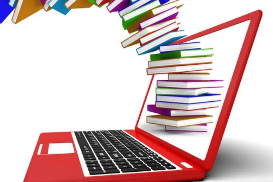 Un computador portátil y en la pantalla se ven libros
