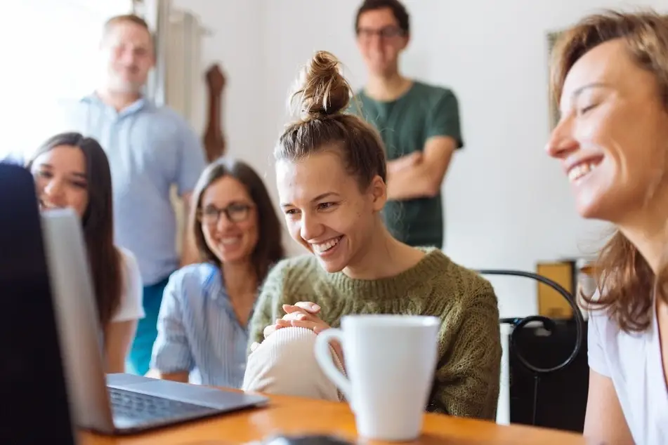 Grupo de personas reunidas mirando juntas la pantalla de una laptop