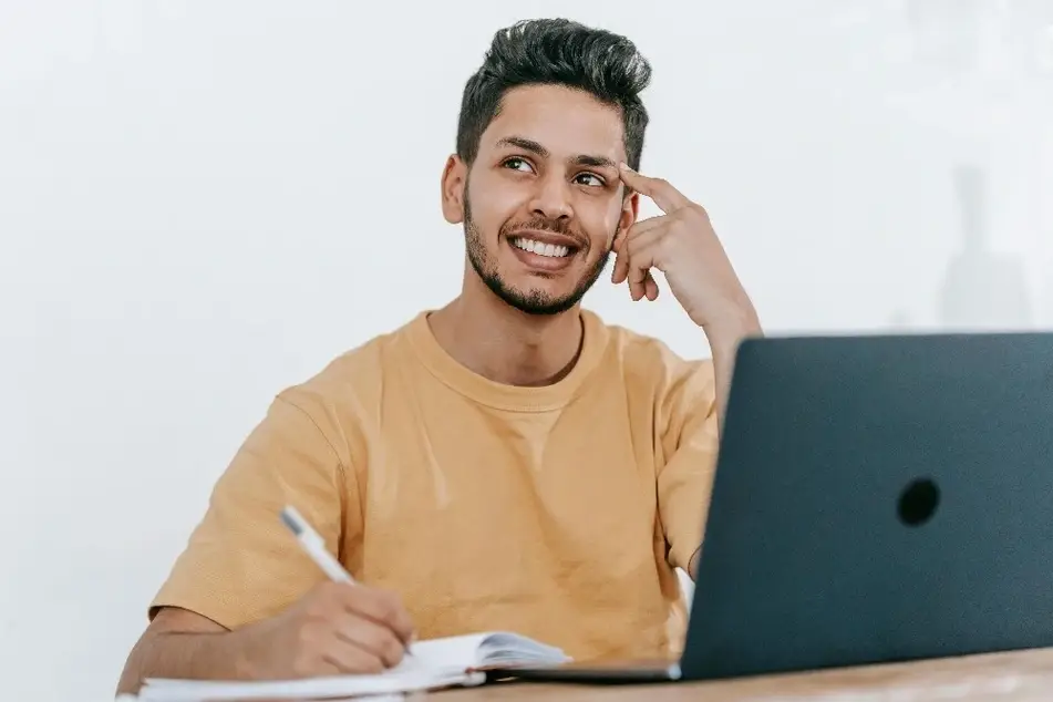 Hombre joven pensando junto a una computadora